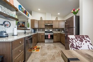 A modern kitchen with wooden cabinets, stainless steel appliances, and a clock on the wall. - The Chile Pad is a charming remodeled 3 bedroom, 2 bathroom townhouse. (Las Cruces)