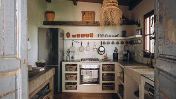 Une cuisine compacte dotée d’un four encastré, d’un porte-casseroles suspendu et d’un plafond en bois rustique.