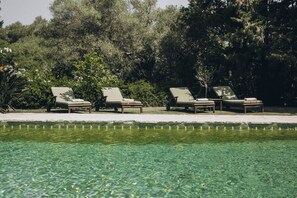 A poolside area with lounge chairs and a clear pool.