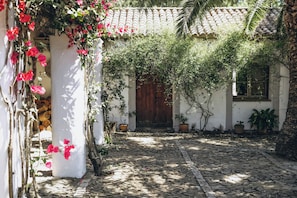 A courtyard with a tiled roof, a wooden door, and potted plants. - The Stable Cottage at Cortijo El Aguilón (Cádiz)