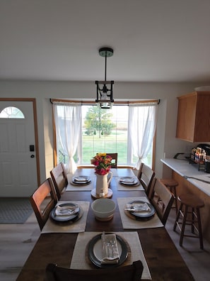 A dining room with a table set for six, a vase with flowers, and a view of the outdoors. - Private Hilltop Oasis with Breathtaking panoramic views. (BISMARCK)