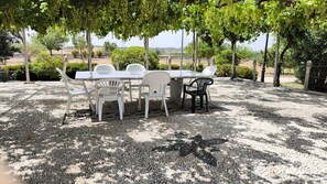 An outdoor dining area with a table and chairs, surrounded by gravel and trees.