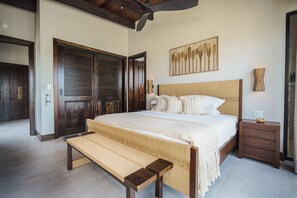 Una camera da letto con un grande letto, una panca, porte in legno e un'opera d'arte appesa al muro.