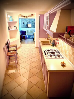 A kitchen with a gas stove, cabinets, and a dining area in the background.