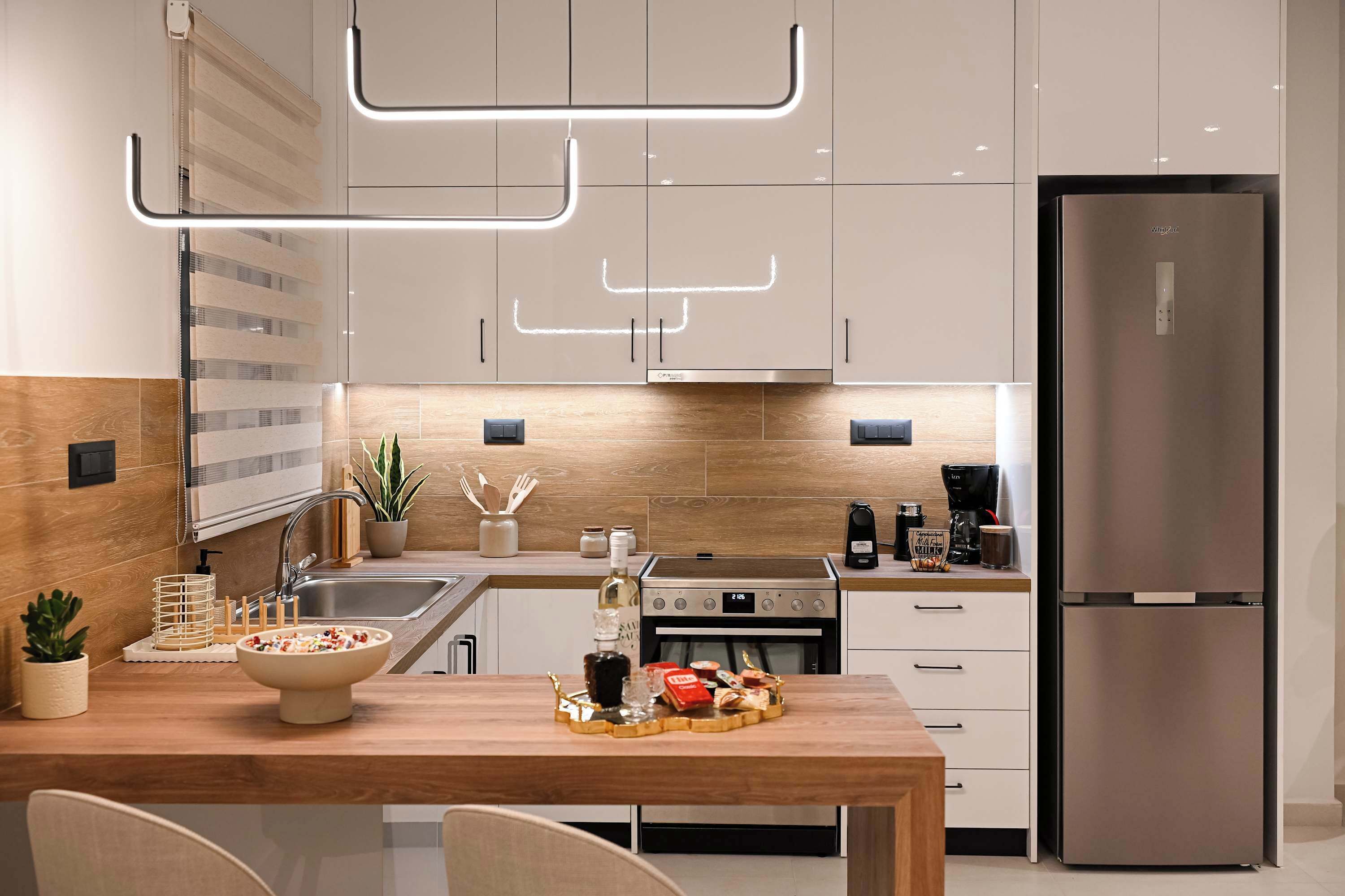 A modern kitchen with a stainless steel refrigerator, a built-in oven, and a dining area with a wooden table and chairs.