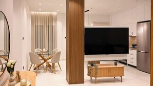 A modern living room with a glass dining table, a wooden coffee table, and a flat-screen TV mounted on the wall. - Light & Kozy Residence - Jacuzzi Lux Stay in Patra (Patra)