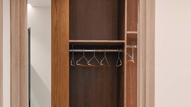 A wooden wardrobe with a mirrored door, a hanging rod, and a lower shelf. - Light & Kozy Residence - Jacuzzi Lux Stay in Patra (Patra)