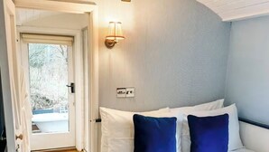 A hotel room with a bed, a nightstand, a lamp, and a door leading to a balcony.