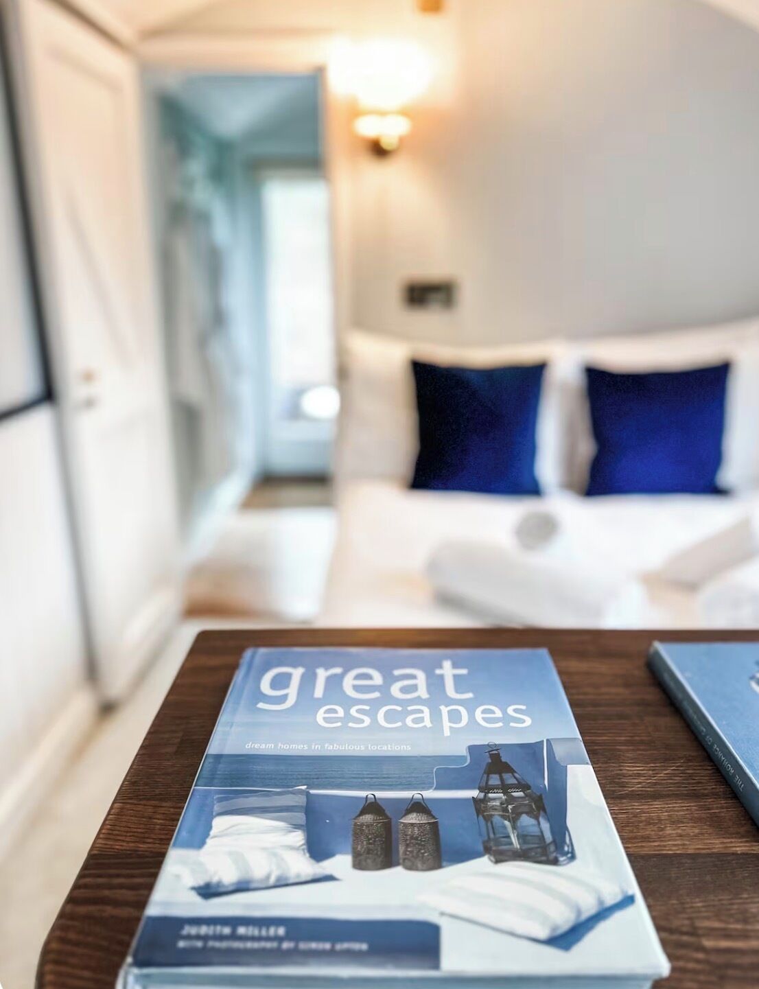 A book titled 'great escapes' on a wooden table in a hotel room.