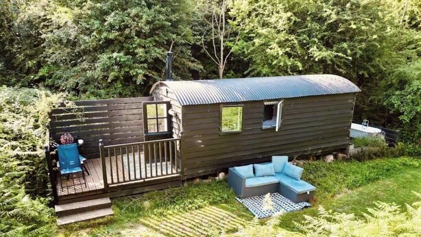 A wooden cabin with a deck, a small window, and a sofa.