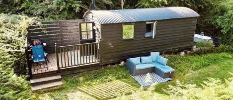 A wooden cabin with a deck, a small window, and a sofa.