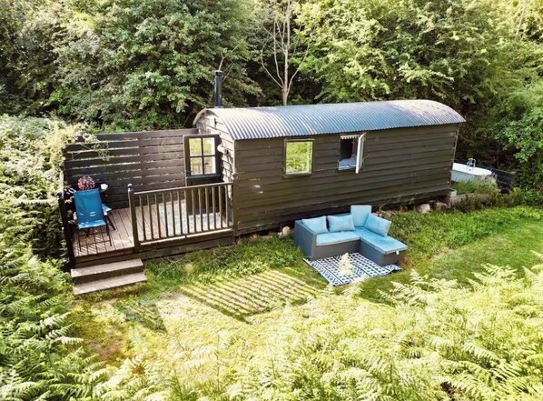 A wooden cabin with a deck, a small window, and a sofa.
