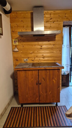 A wooden kitchen with a built-in stove, a wooden cabinet, and a tiled backsplash. - Graziosa casa di montagna (Noasca)