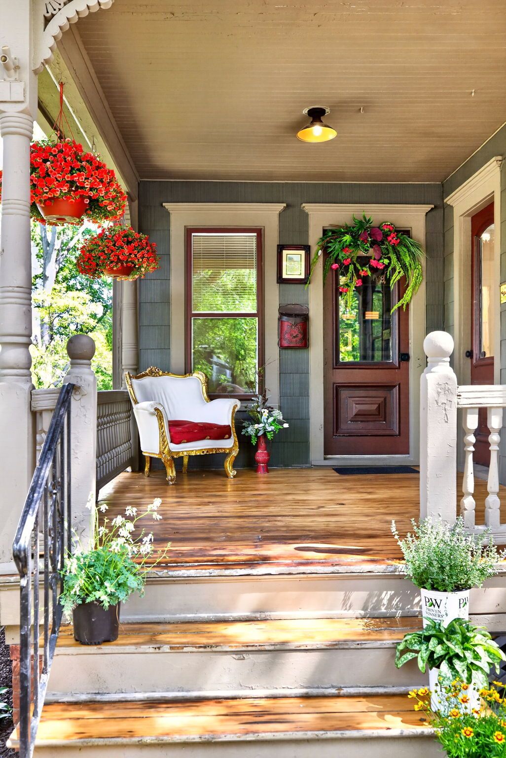 A porch with a white chair, a wooden floor, and potted plants.