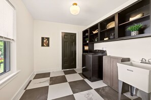 Een moderne keuken met een zwart-wit geruite vloer, een inbouwvaatwasser en een witte spoelbak met kraan.