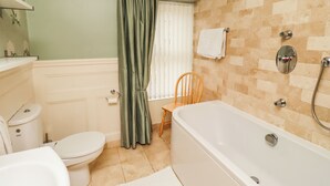 Ein Badezimmer mit Toilette, Badewanne, Dusche und einem Sessel.