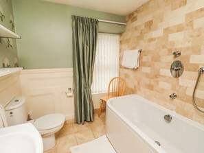 Ein Badezimmer mit Toilette, Badewanne, Dusche und einem Sessel.