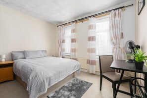 A bedroom with a bed, bedside table, chair, and a small table with a plant. - Stratford 3-bed House, Sleeps 7 With Garden (London)