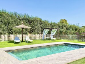A swimming pool with a wooden deck, two sun loungers, a pergola with white curtains, and a wooden fence. - El Bancal Farm (AN)