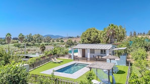 Uma casa moderna com piscina, jardim murado e vista para a paisagem ao redor.