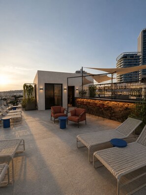 A rooftop terrace with lounge chairs, a bar area, and a view of the cityscape. - Ross Street Hotel (St. Julian's)