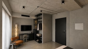 A modern bedroom with a bed, a desk, a chair, a TV, and a wardrobe. - Ross Street Hotel (San Ġiljan)