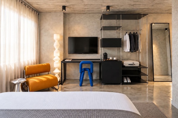 Una habitación de hotel moderna con cama, escritorio, silla, televisor y armario.
