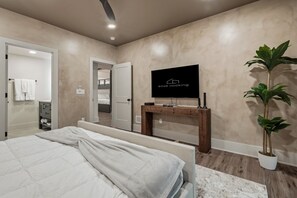 A modern bedroom with a bed, a TV on a wooden stand, and a potted plant. - The Rock Haus | Pool, Putt-Putt | Hocking Hills (Laurelville)