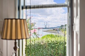 Udsigt fra et vindue over en flod med bygninger, et lampe og grønt.