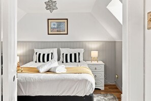 A bedroom with a bed, bedside tables, a lamp, and a framed picture on the wall.
