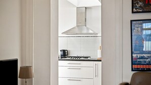 A modern kitchen with white cabinetry, a stainless steel range hood, and a gas stove. - West Beach Cottage - Large Garden and Tay Views (Dundee)