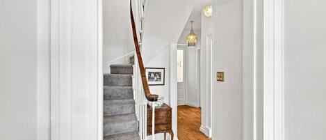 A staircase with a wooden handrail leading to a landing with a picture frame.