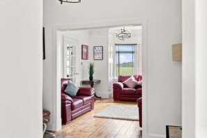 A spacious living room with two leather sofas, a small round table, and a potted plant.