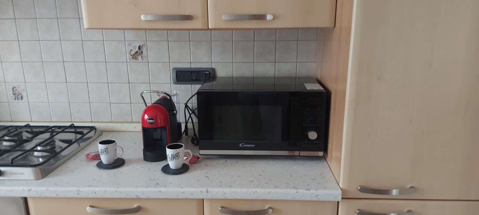 Eine Küche mit Gasherd, Kaffeemaschine, Mikrowelle und einer Kaffeetasse auf der Arbeitsfläche.