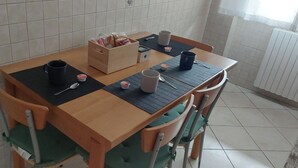 A dining table with chairs, a box of bread, a black mat, and a cup. - Two-room apartment just a few minutes from the Rho Fiera Milan exhibition center, ideal for families and working professionals (Pregnana Milanese)