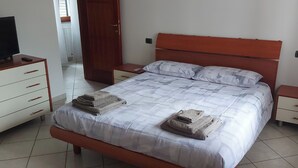 A bedroom with a bed, a TV on a dresser, and a door. - Two-room apartment just a few minutes from the Rho Fiera Milan exhibition center, ideal for families and working professionals (Pregnana Milanese)