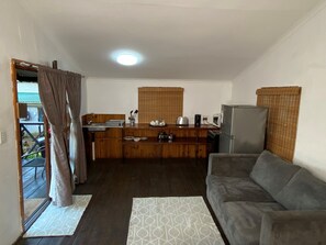Un espacio habitable compacto con kitchenette, un sofá y un comedor.