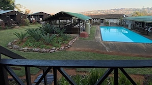 Zona residencial con piscina, cabañas de madera y vistas a un pueblo lejano.