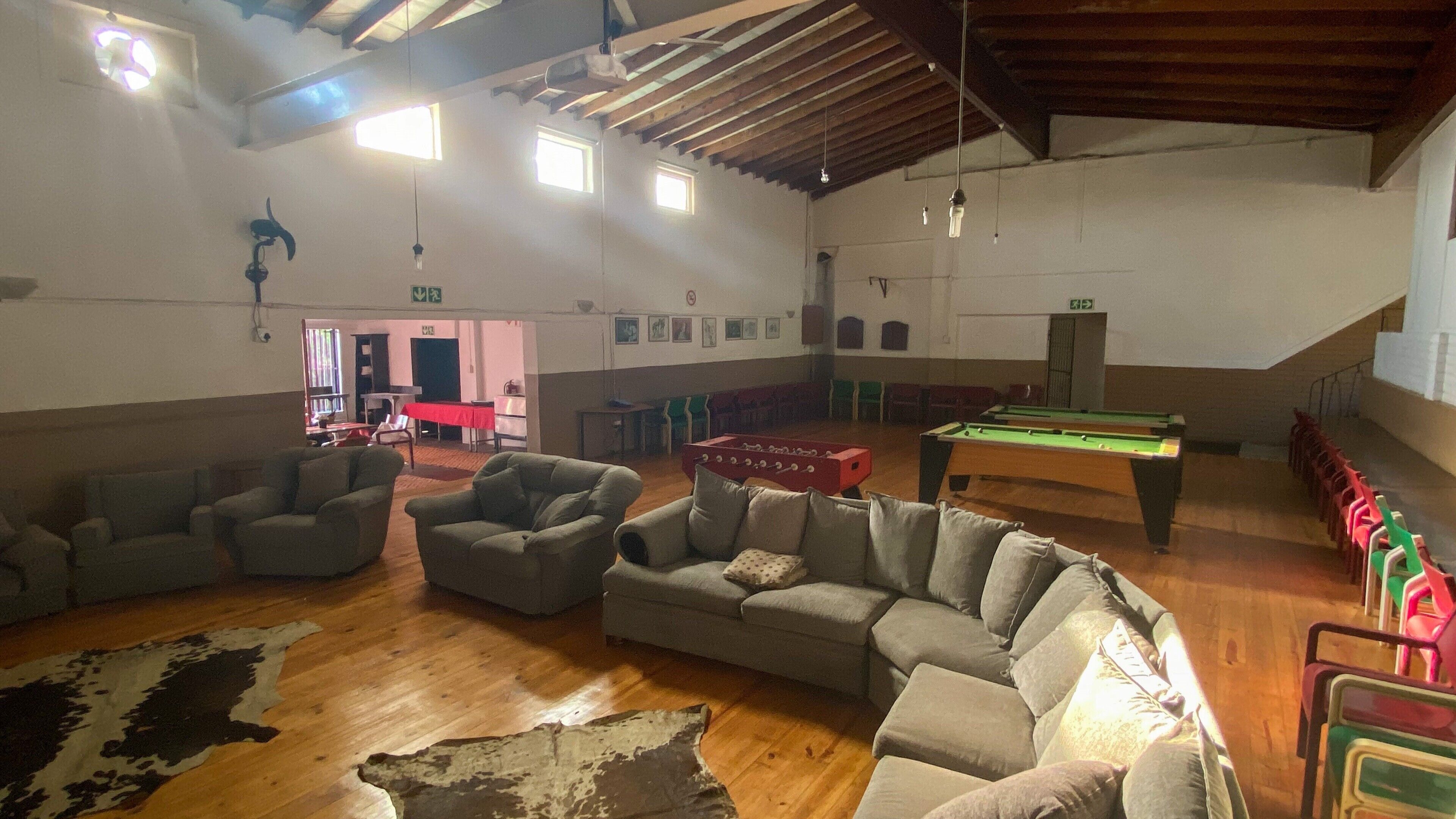 A spacious indoor area with sofas arranged in a semi-circle, a pool table, and a foosball table.