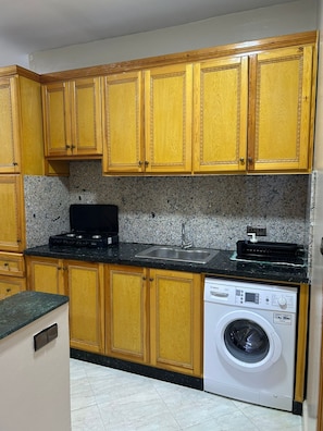 A kitchen with wooden cabinets, a black countertop, a stainless steel sink, and a white Bosch washing machine.