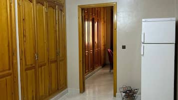 A hallway with wooden cabinets, a white refrigerator, and a tiled floor.