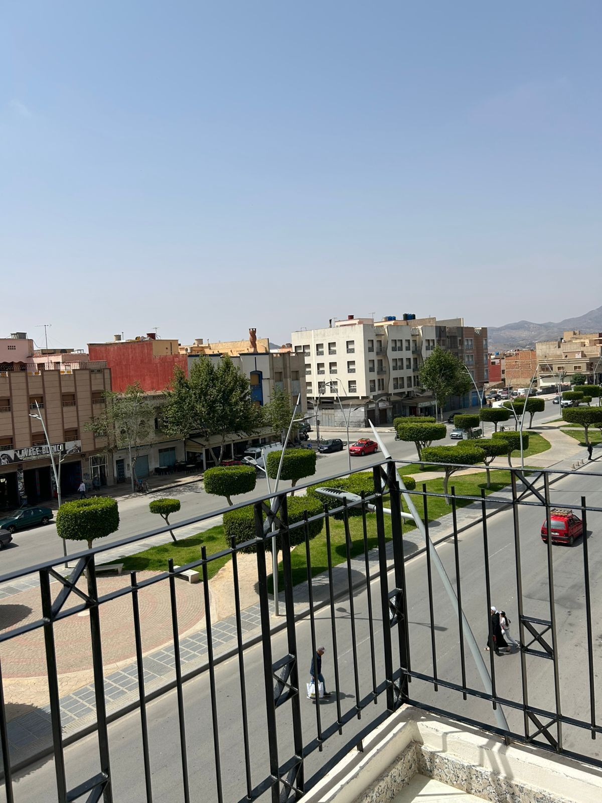 A street view with buildings, a clear sky, and a pedestrian walkway.