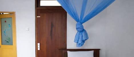 A room with a bed, a wooden door, and a blue canopy.
