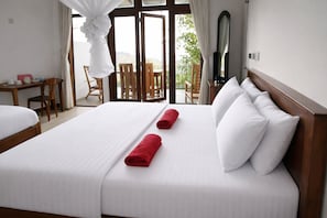 A hotel room with a large bed, two red towels, a wooden headboard, and a view of the outdoors.