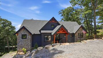 Ein zweistöckiges Haus mit einer Stein-Fassade, einem dunklen Dach und einer amerikanischen Flagge.