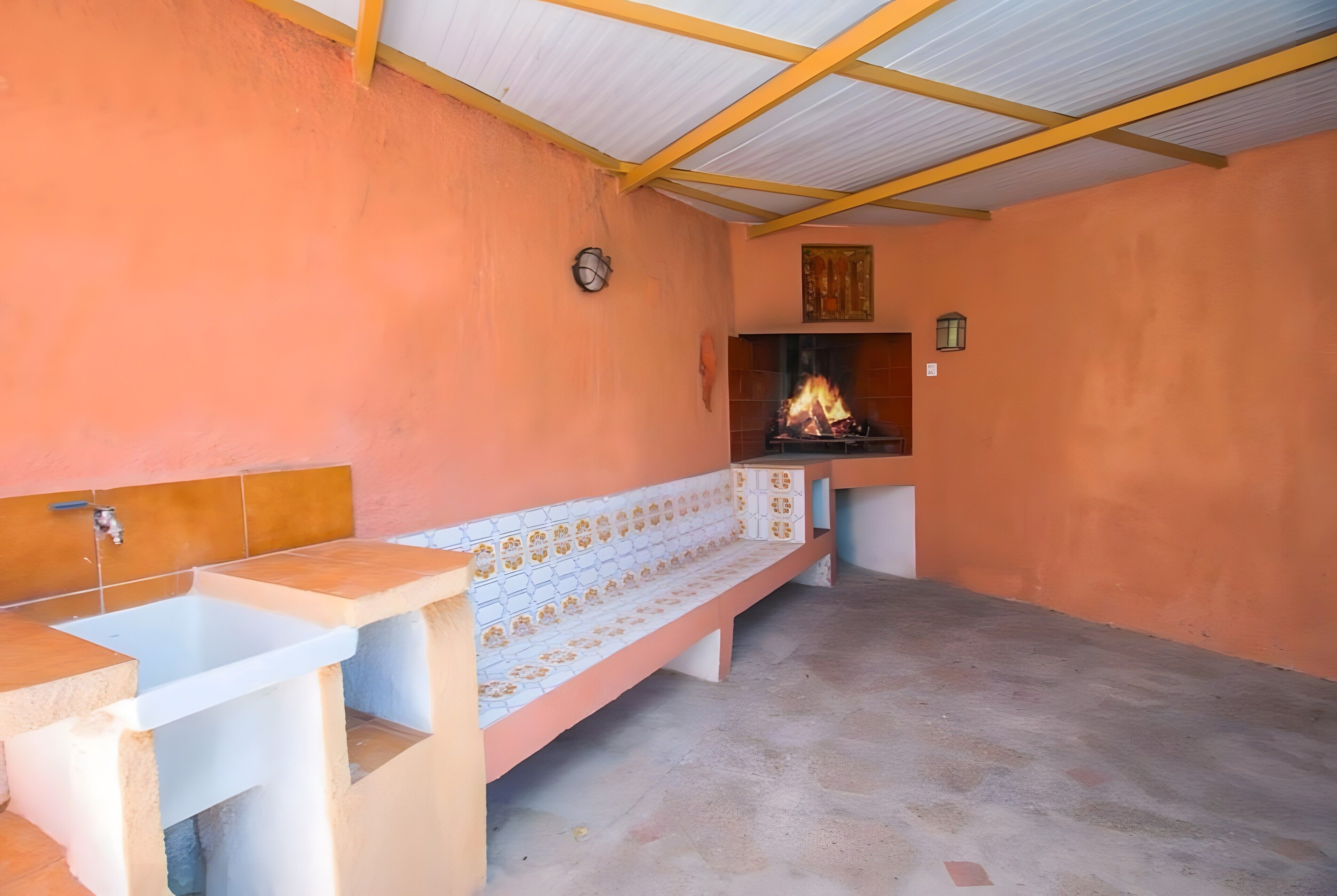 A room with a fireplace, a bench, and a sink.