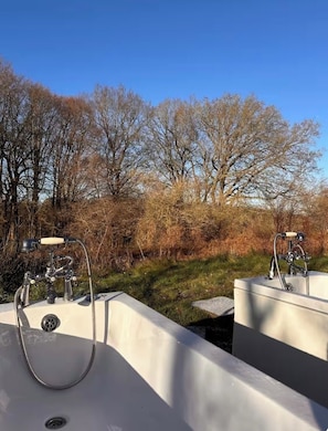 Two outdoor sinks with faucets and hoses, surrounded by trees and shrubs. - Elegant Hideaway| Twin baths under the stars (Doddington)