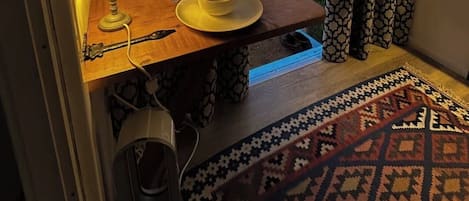 Un coin repas avec une table dressée pour deux personnes, une lampe et une vue sur l’extérieur.