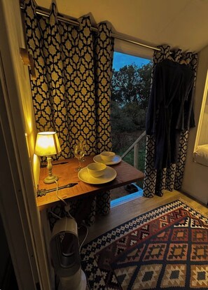 Een eetgedeelte met een tafel voor twee, een lamp en uitzicht op het omliggende landschap.