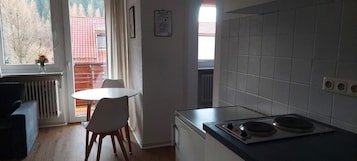 A compact kitchen with a dining table, a chair, and a stove.